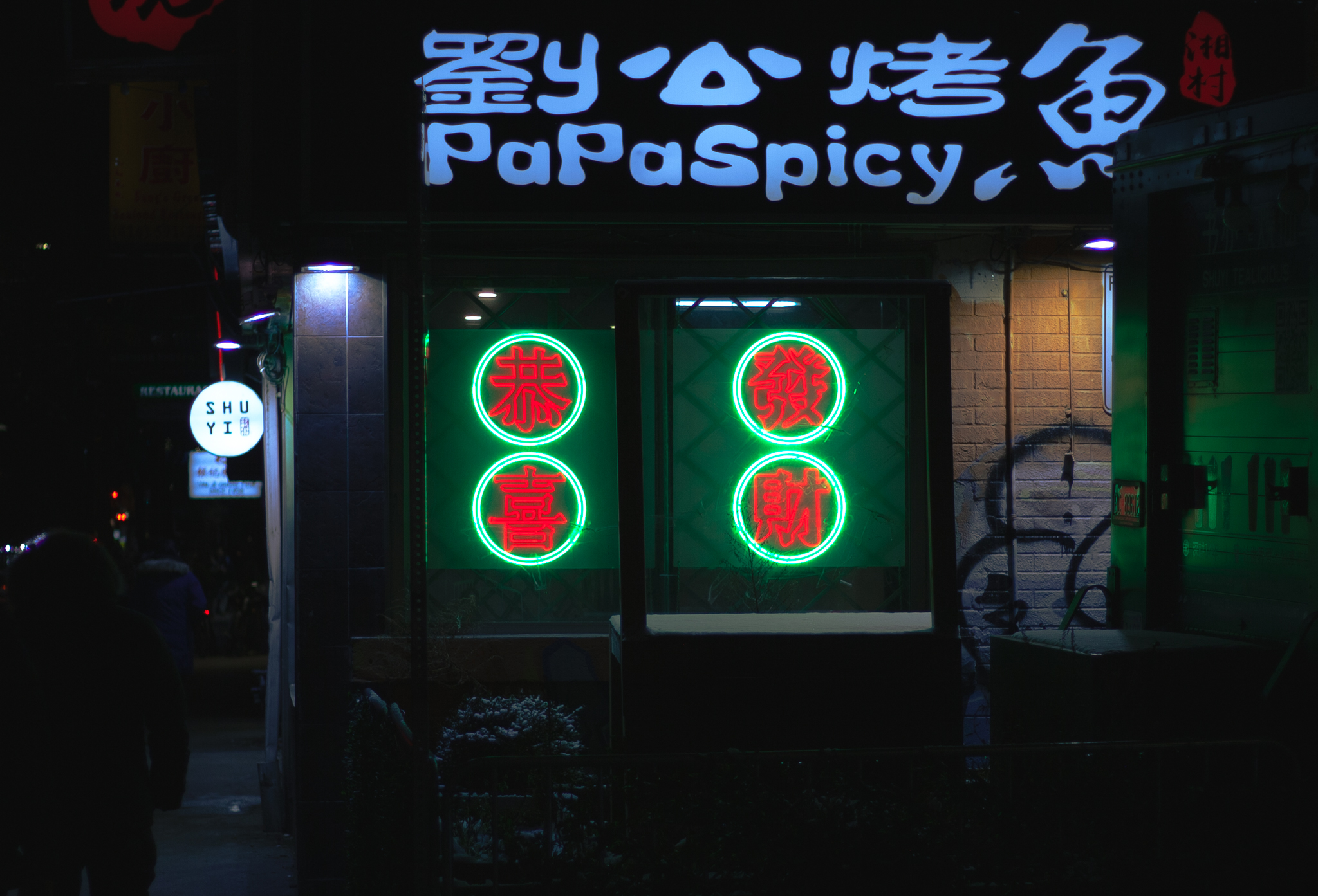 Green and red glowing neon sign on the side of a restaurant