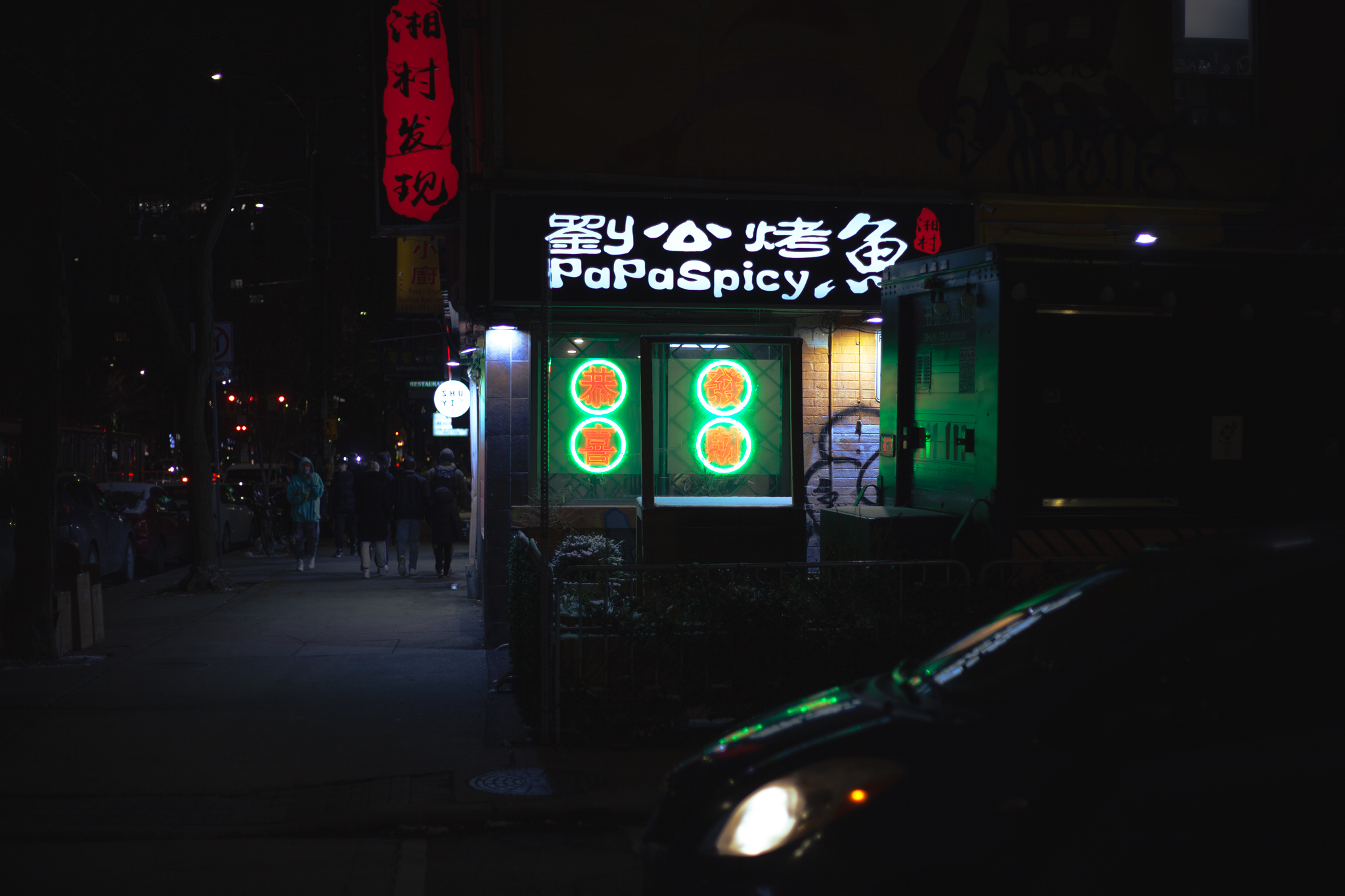 Green and red glowing neon sign on the side of a restaurant