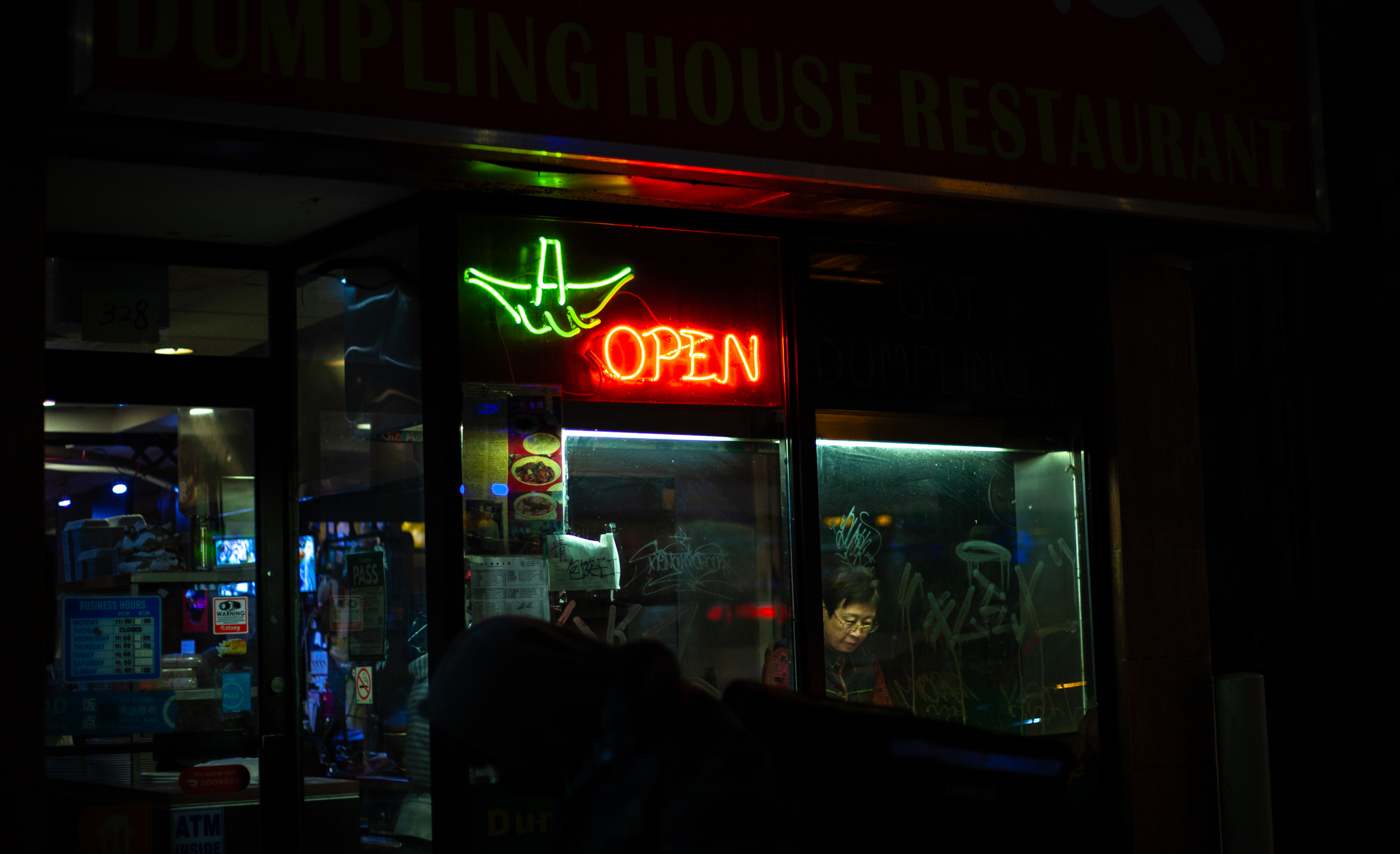 Woman in a storefront window cooks food during the night